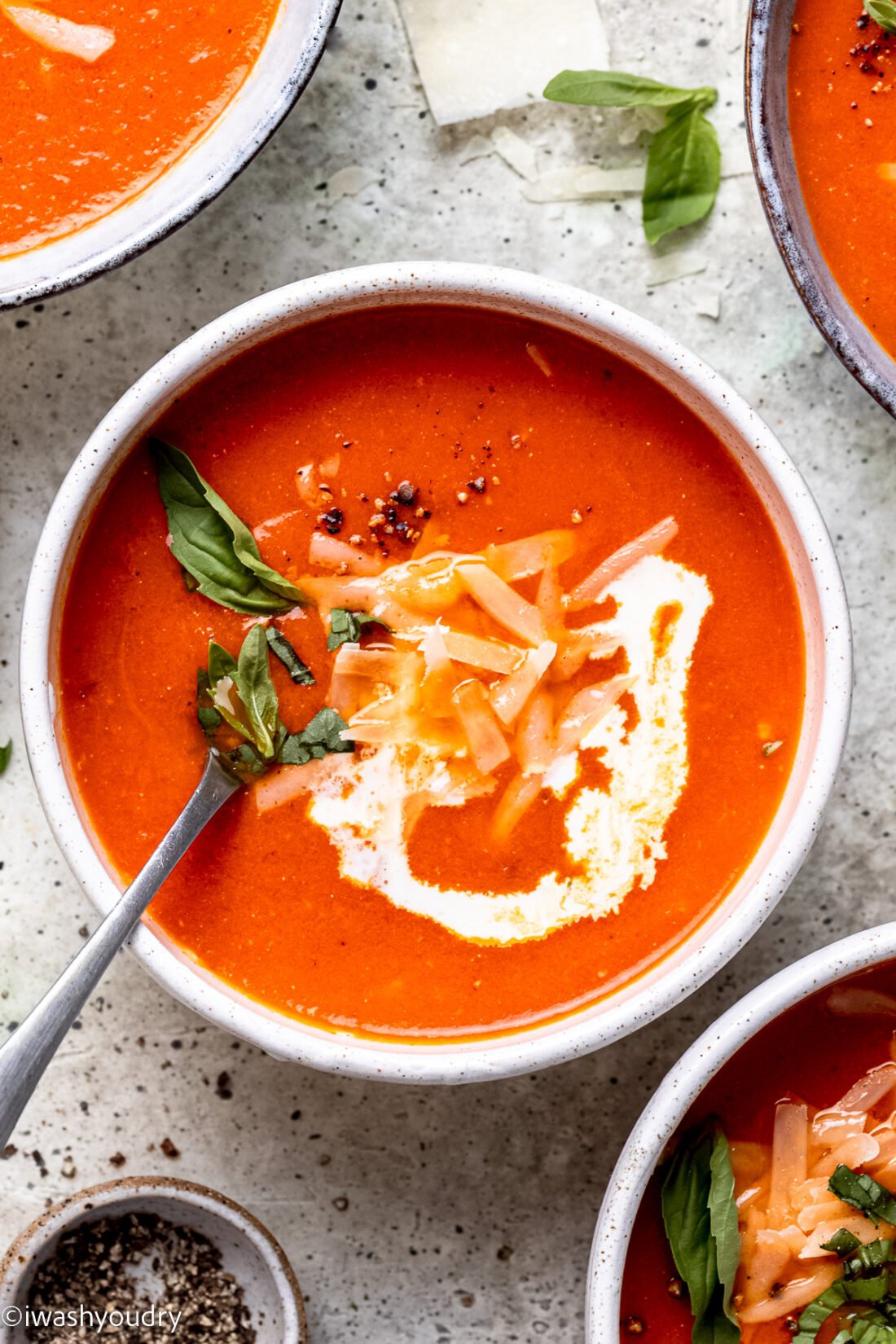 bowl of tomato soup with parmesan cheese and cream on top. 