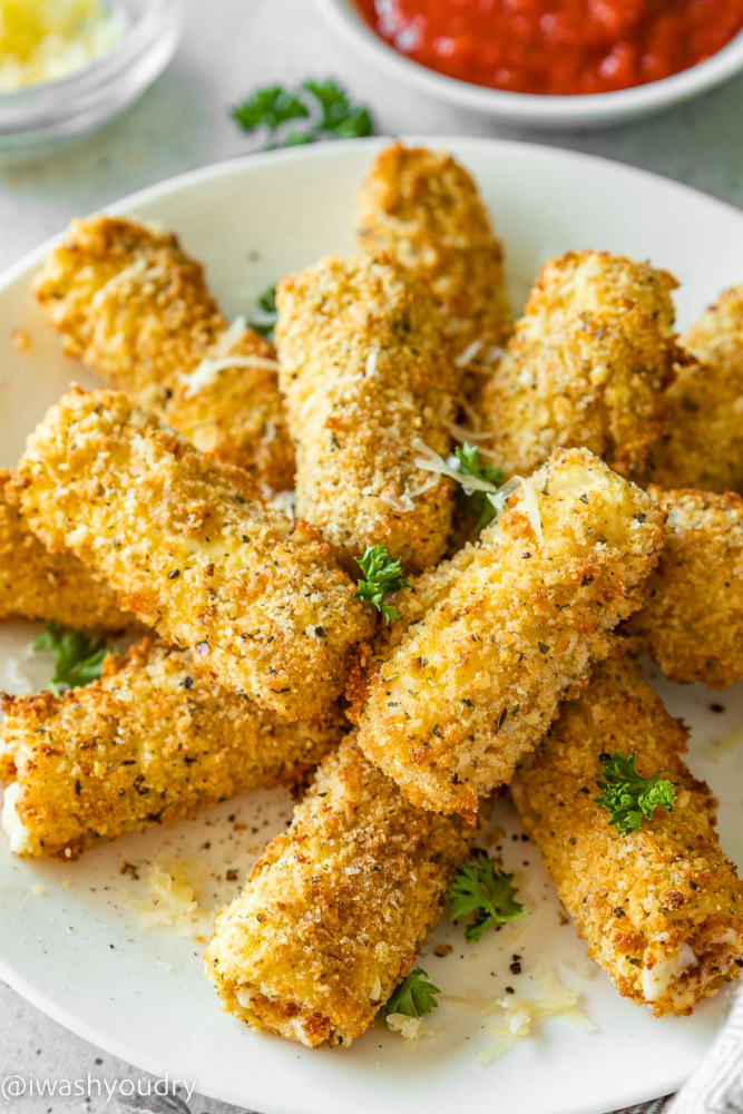 pile of mozzarella sticks on white plate with parmesan cheese.