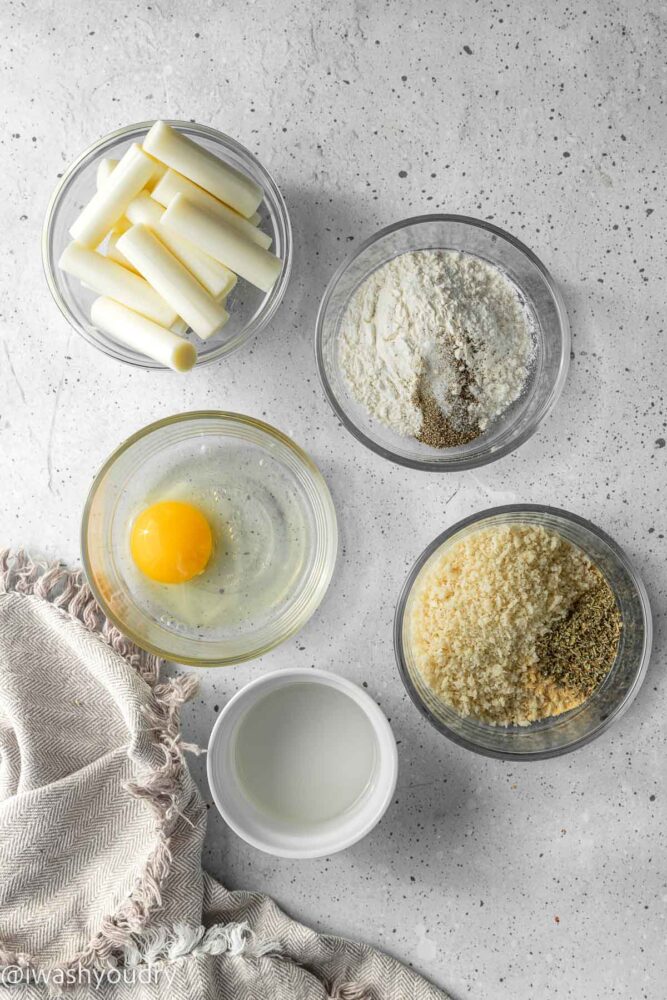 Ingredients for mozzarella sticks on a white surface.