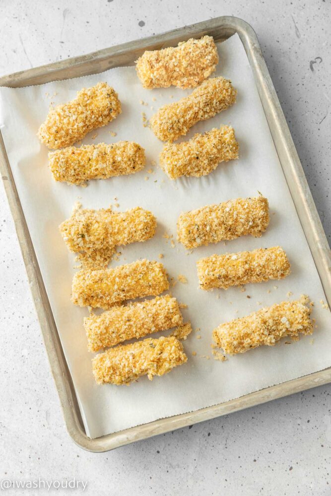 frozen mozzarella sticks on a parchment lined baking sheet.