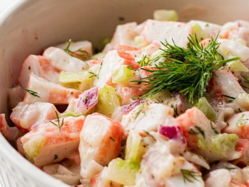 white bowl with creamy crab salad topped with fresh dill weed.
