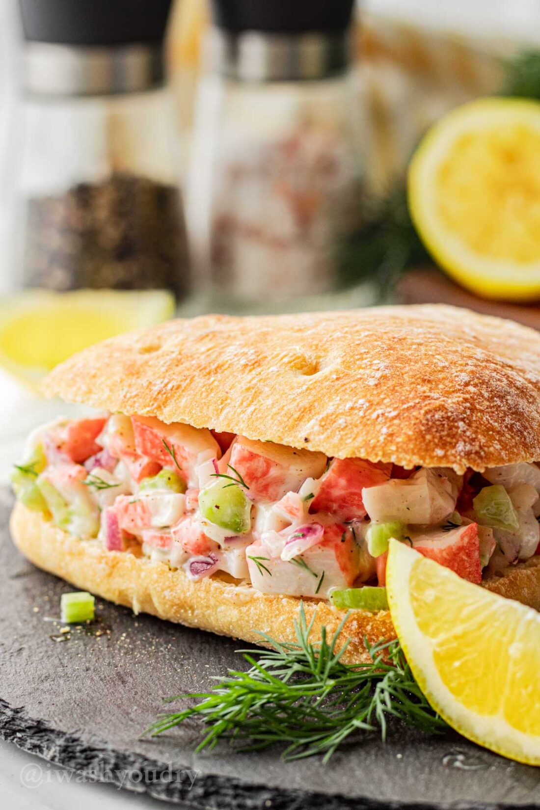 creamy crab salad on a roll with lemon wedge.