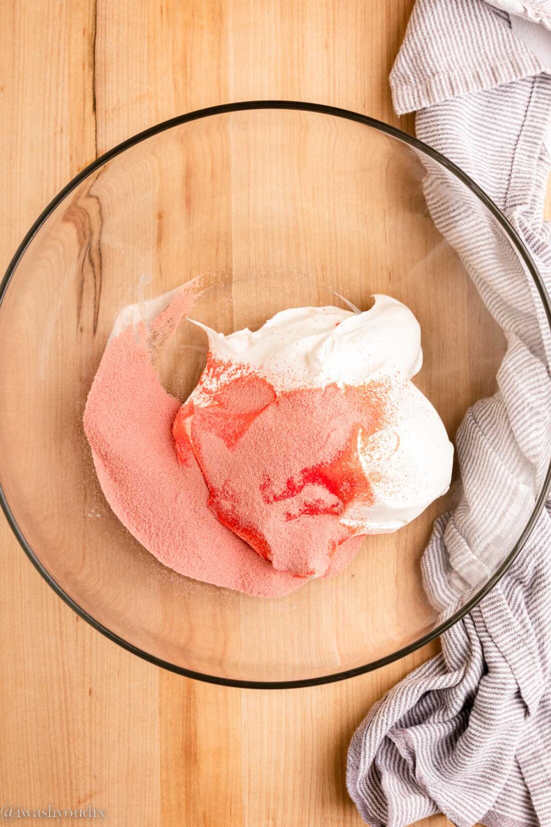 Raspberry Jello Powder and whipped topping in a glass bowl. 