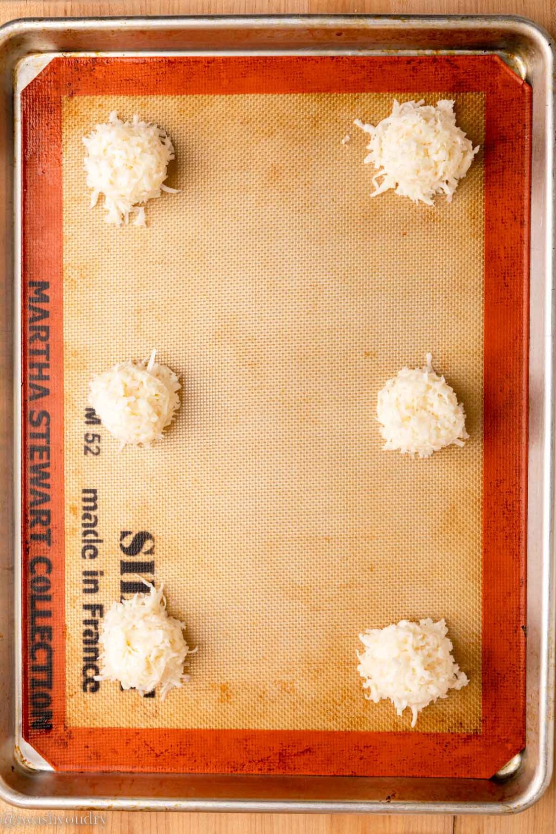 Unbaked coconut macaroon balls on metal baking sheet. 