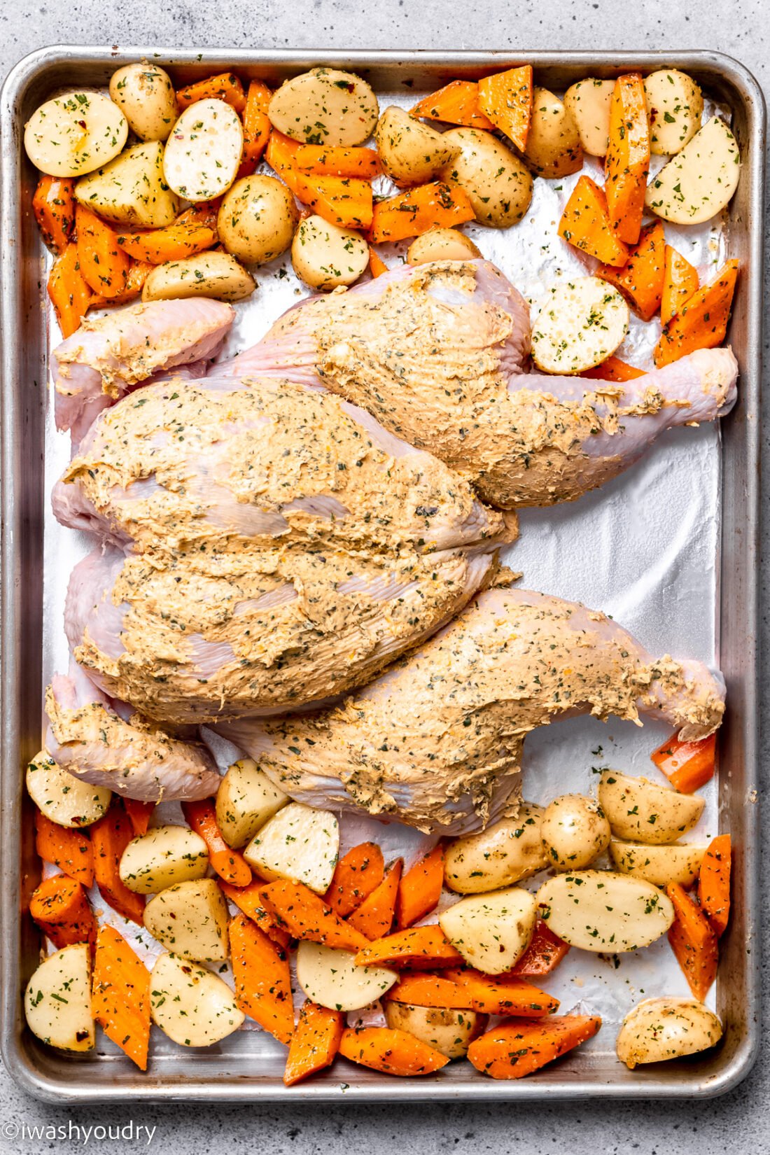 Raw Spatchcock chicken with vegetables on baking sheet. 