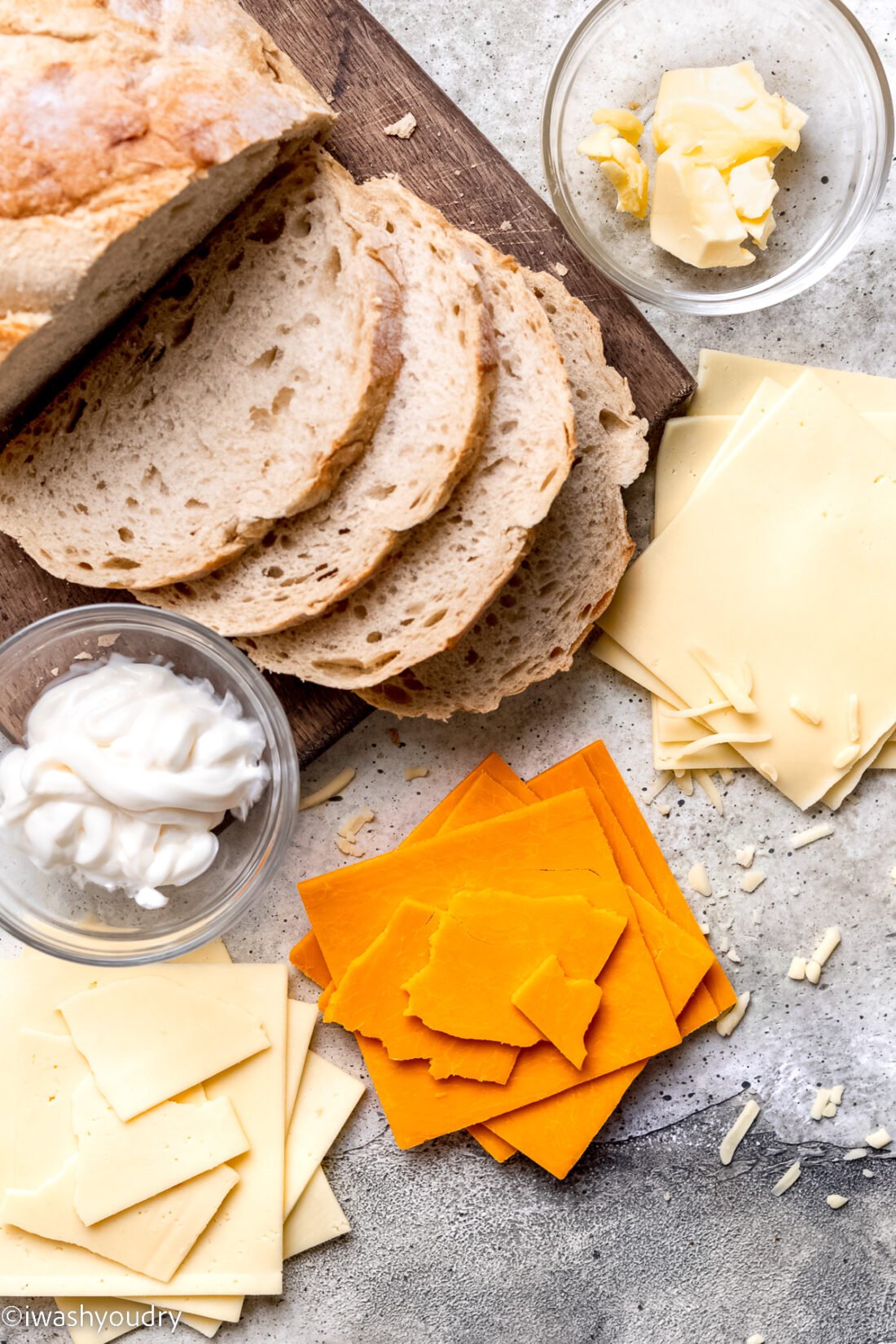 Bread, cheese, and mayo in glass bowls on gray background. 