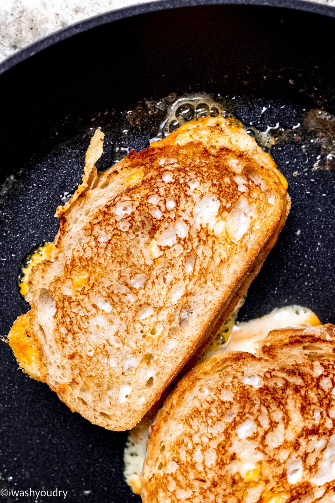 Grilled cheese sandwich in black frying pan. 