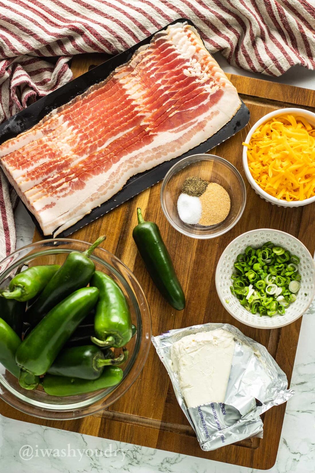 Ingredients for bacon wrapped jalapeno poppers on wood cutting board. 