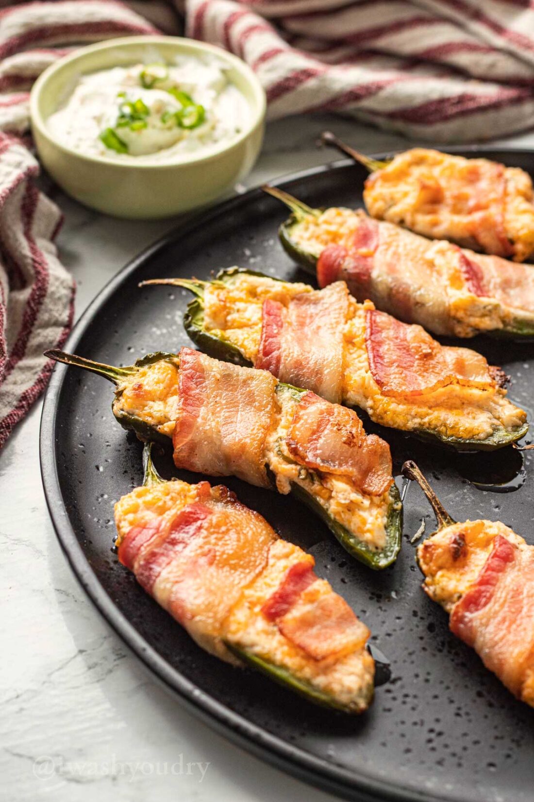 Baked jalapeno poppers on black plate. 