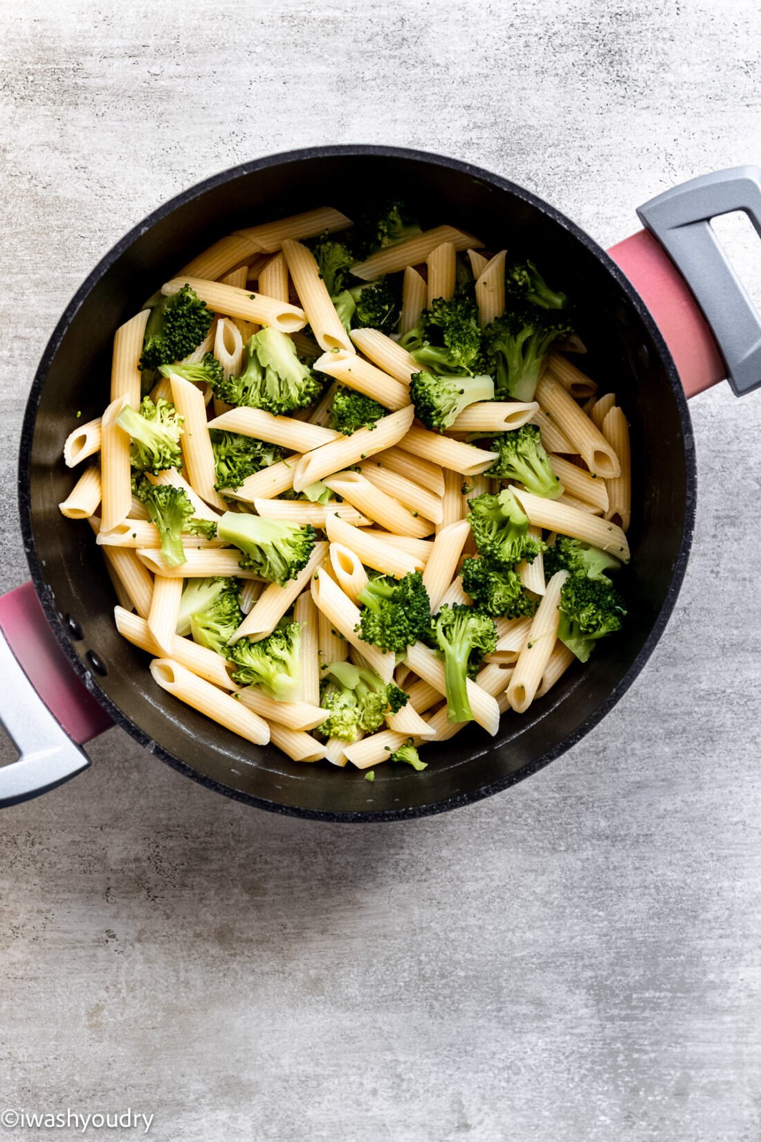 Cooked broccoli and penne in black pot. 