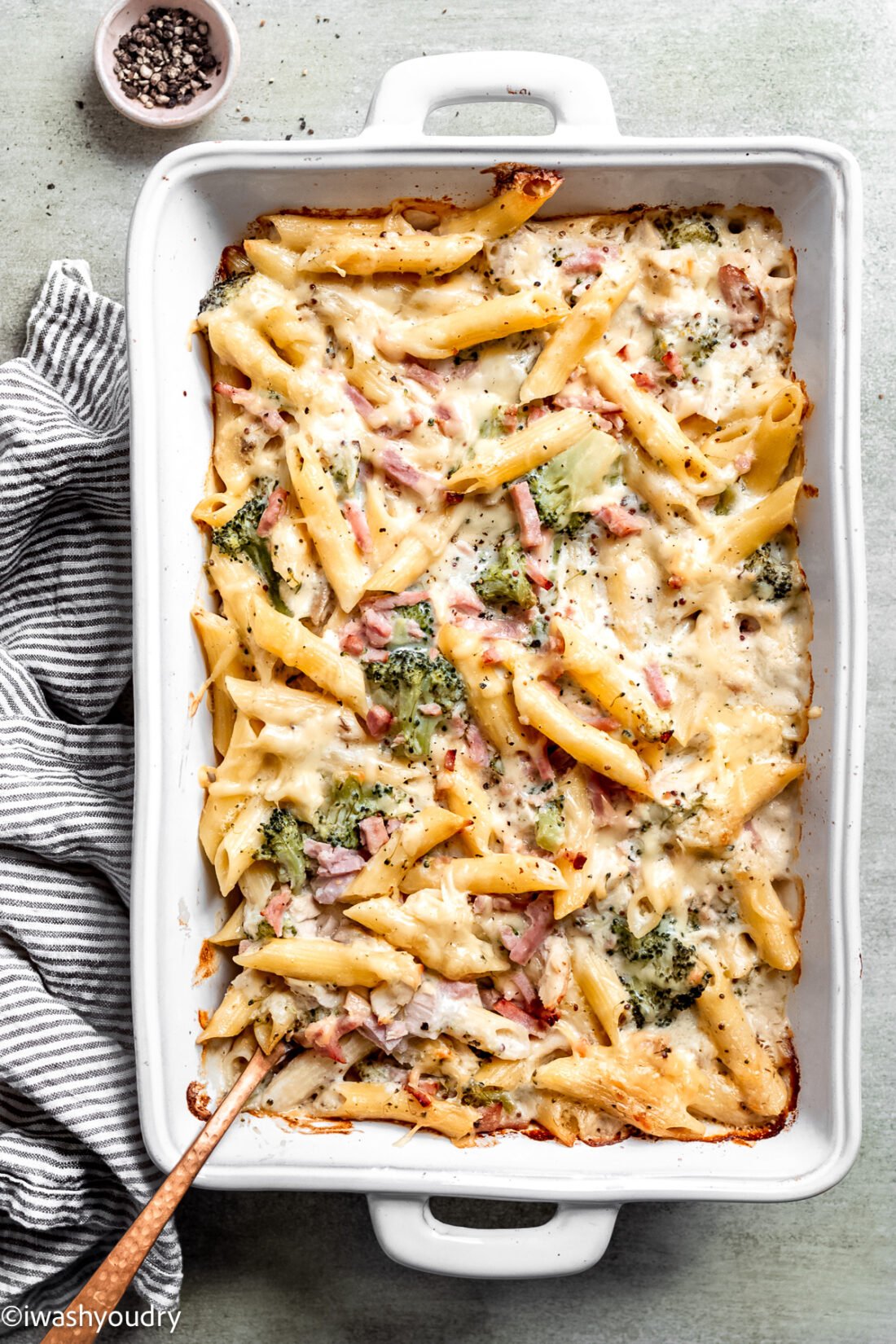 Baked chicken cordon bleu pasta casserole in white dish with spoon. 