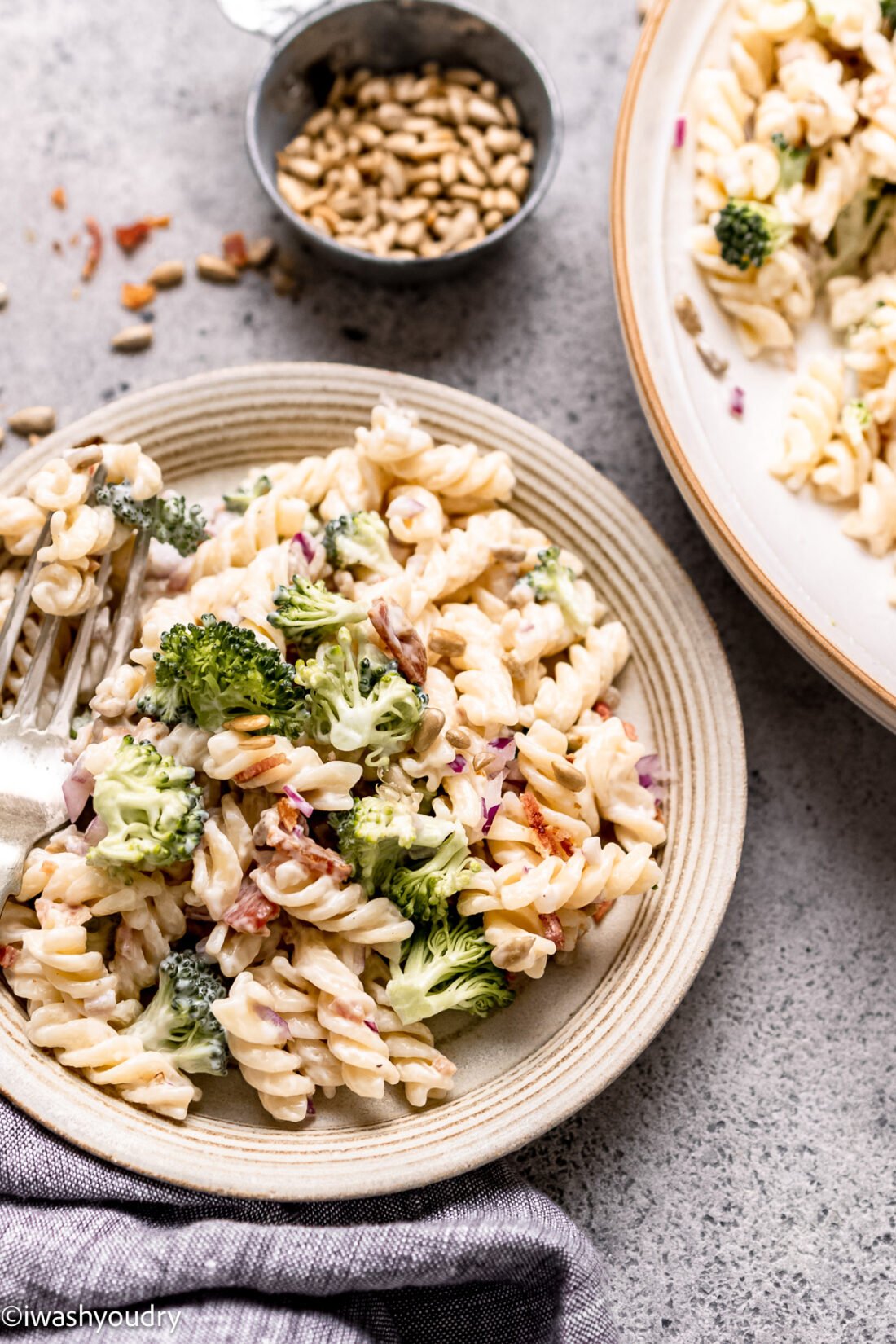 plate of pasta salad with sunflower seeds, bacon and broccoli.