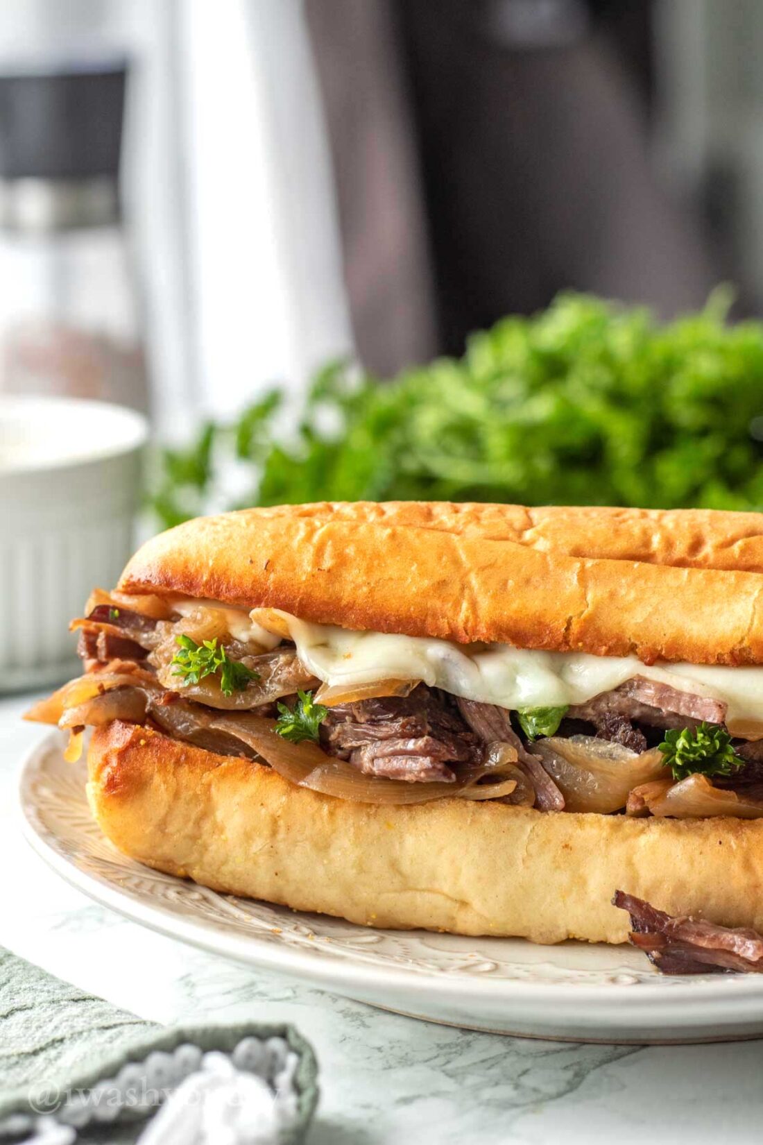 French beef sandwich on toasted roll on white plate. 