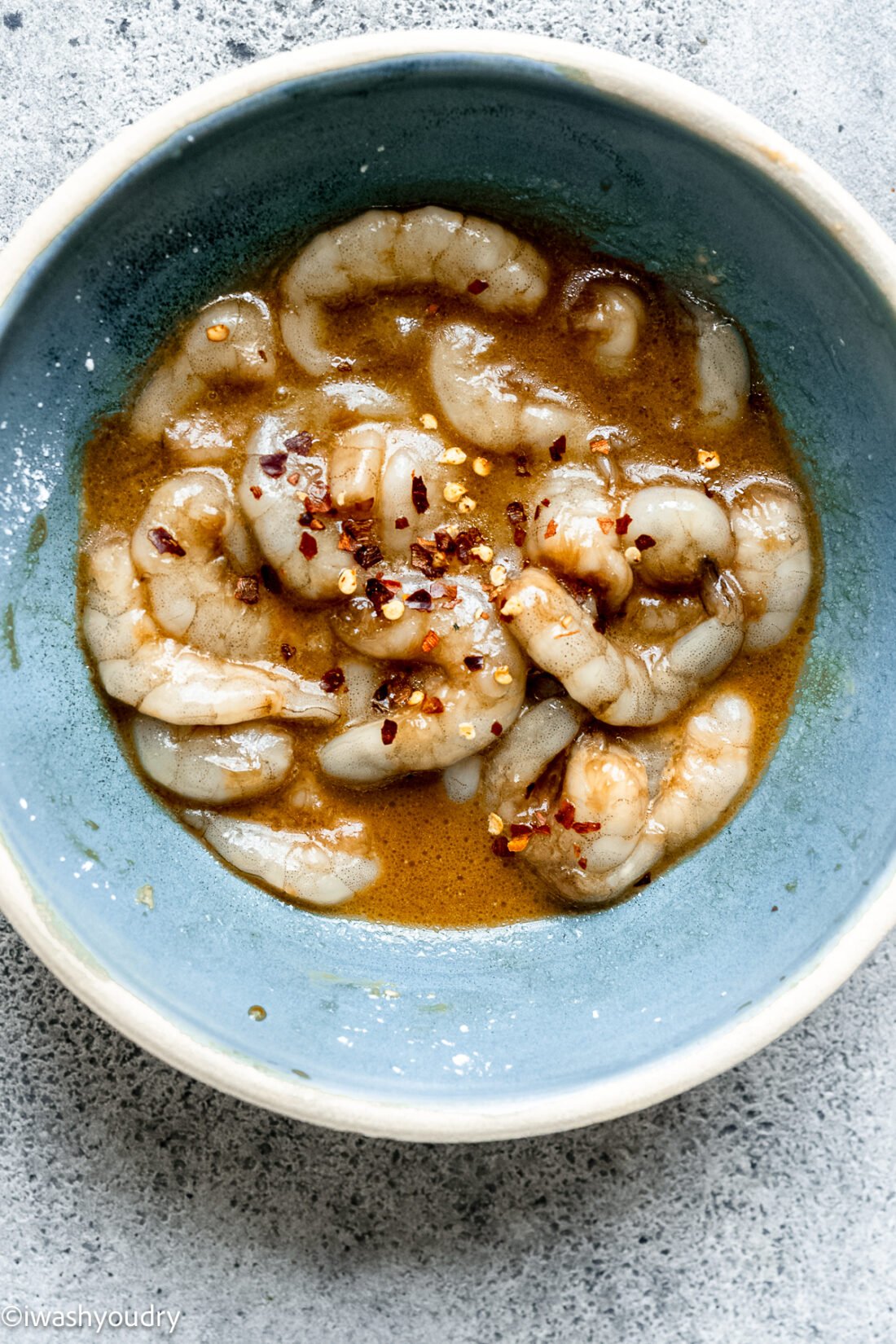 seasoned shrimp in bowl with red pepper flakes.