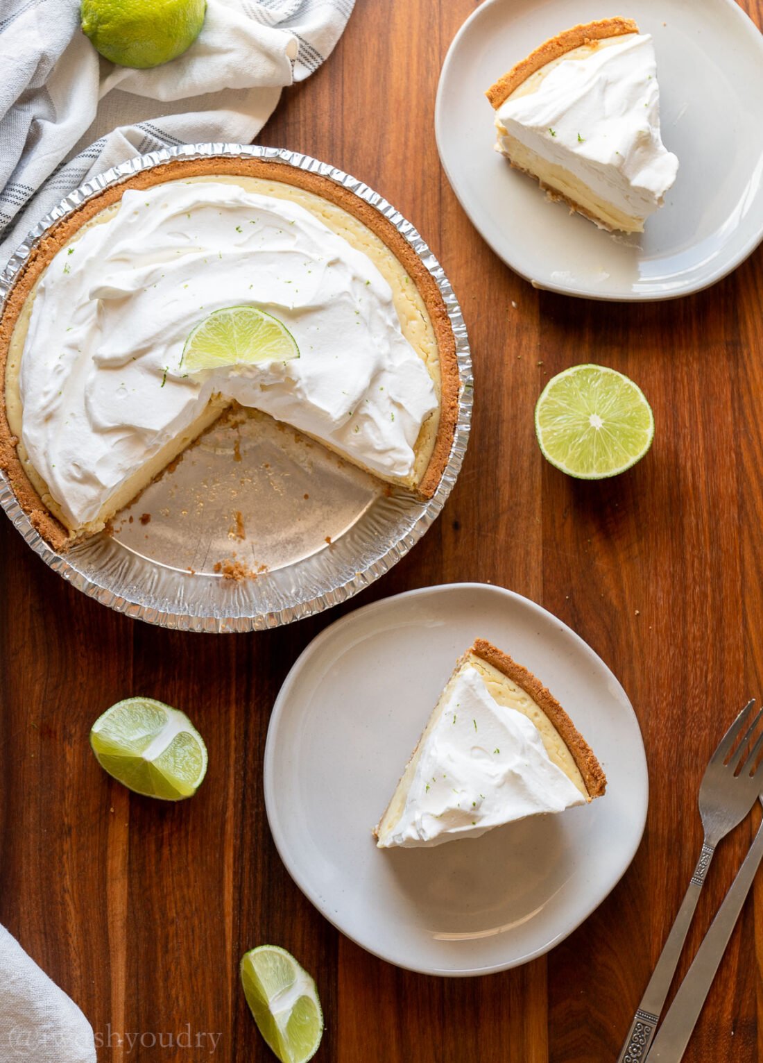 wooden surface with sliced key lime pie on white plates.