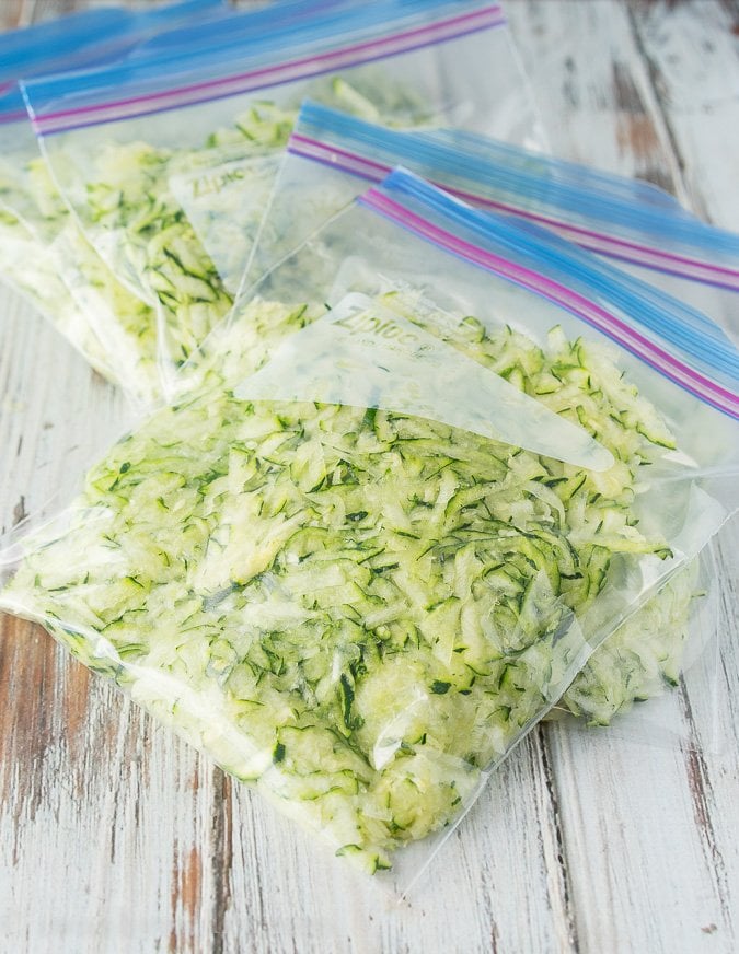 shredded zucchini in zip close bags on white surface.