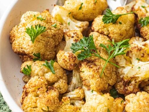 Cooked air fry cauliflower in white bowl with spoon.