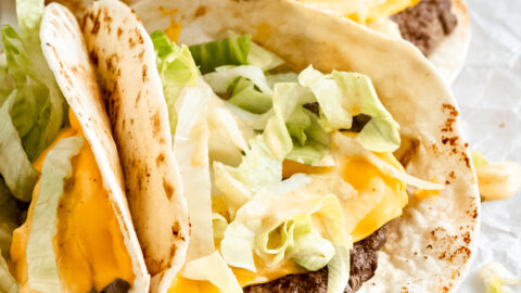three small tacos with beef and cheese topped with lettuce and big mac sauce.