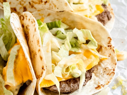 three small tacos with beef and cheese topped with lettuce and big mac sauce.