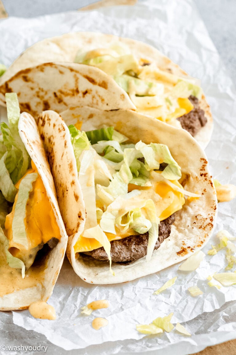 three small tacos with beef and cheese topped with lettuce and big mac sauce.