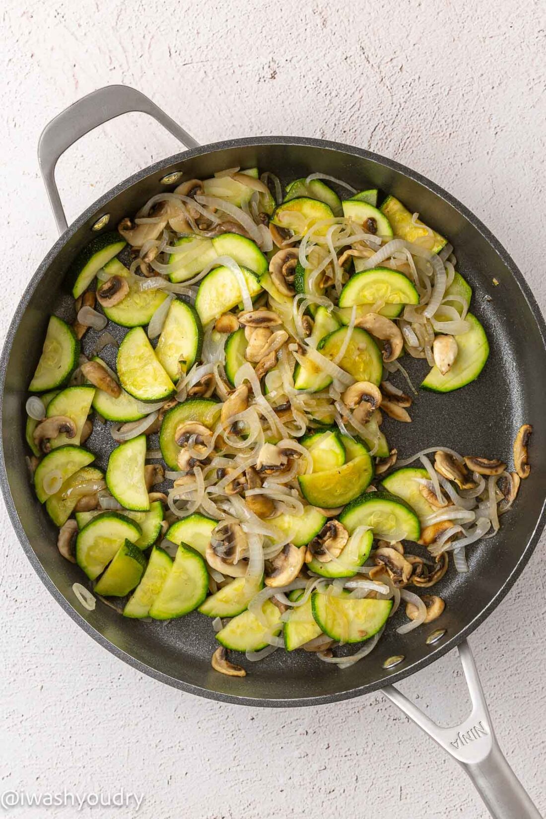 Cooked zucchini onions and mushrooms in a frying pan. 
