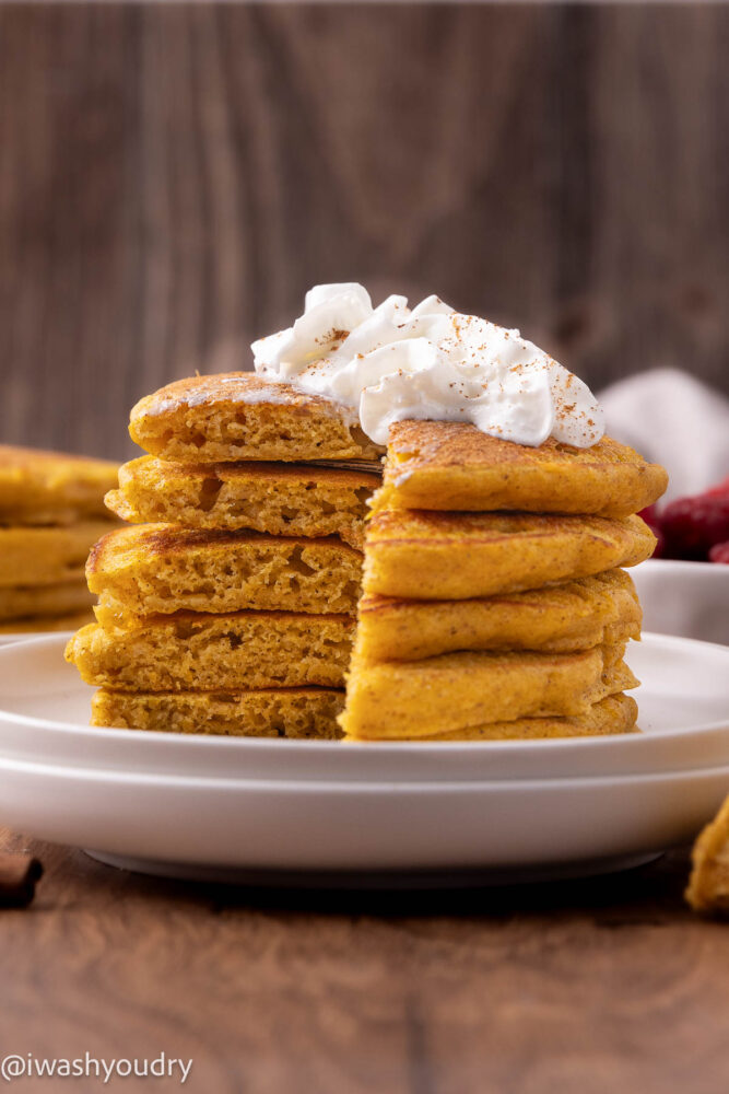 Stack of cooked pumpkin pancakes on white plate.