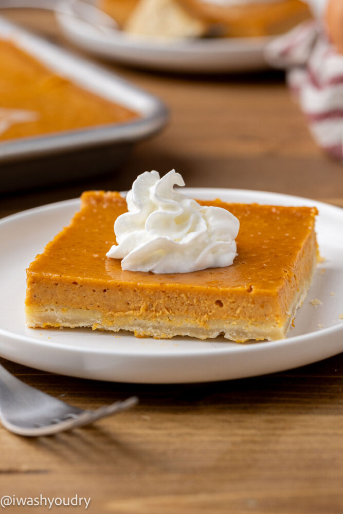 Slice of pumpkin pie bar on a white plate with a fork.