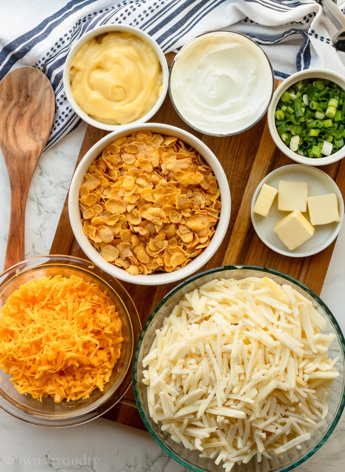 ingredients for casserole potatoes with hashbrowns and onions on wooden surface.