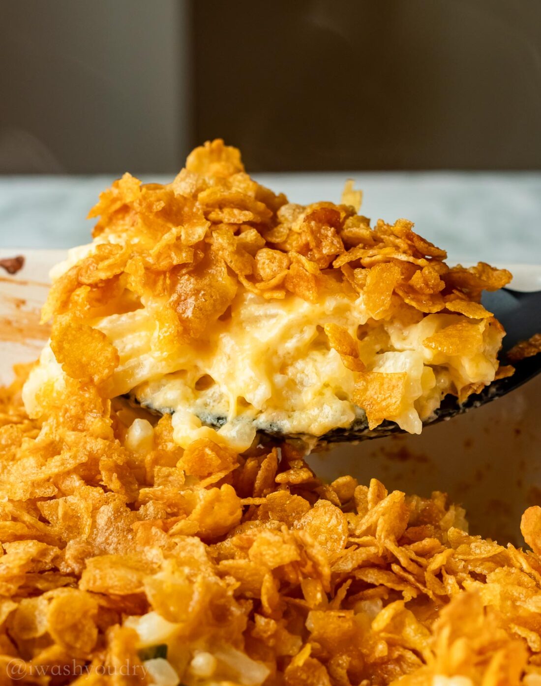 spoonful of potato casserole with cornflakes on top.