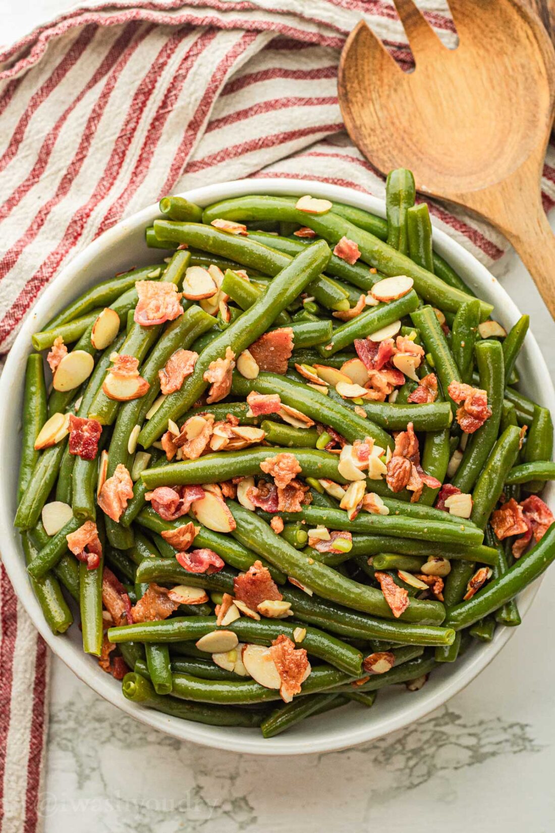 white serving dish with green beans and bacon.