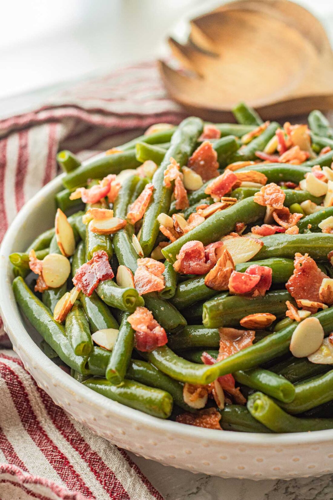 southern style green beans with bacon and almonds in white bowl with spoon.