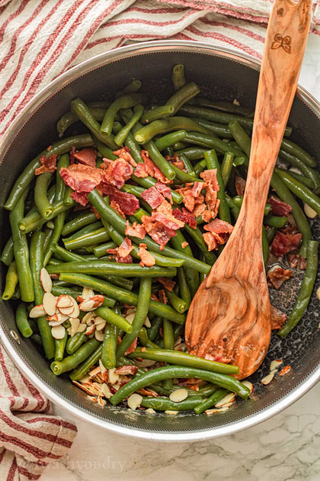 black skillet with green beans, bacon and almonds.