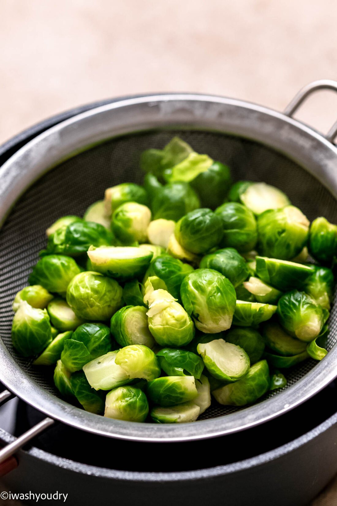 Cooked brussels sprouts in steamer basket in metal pot. 