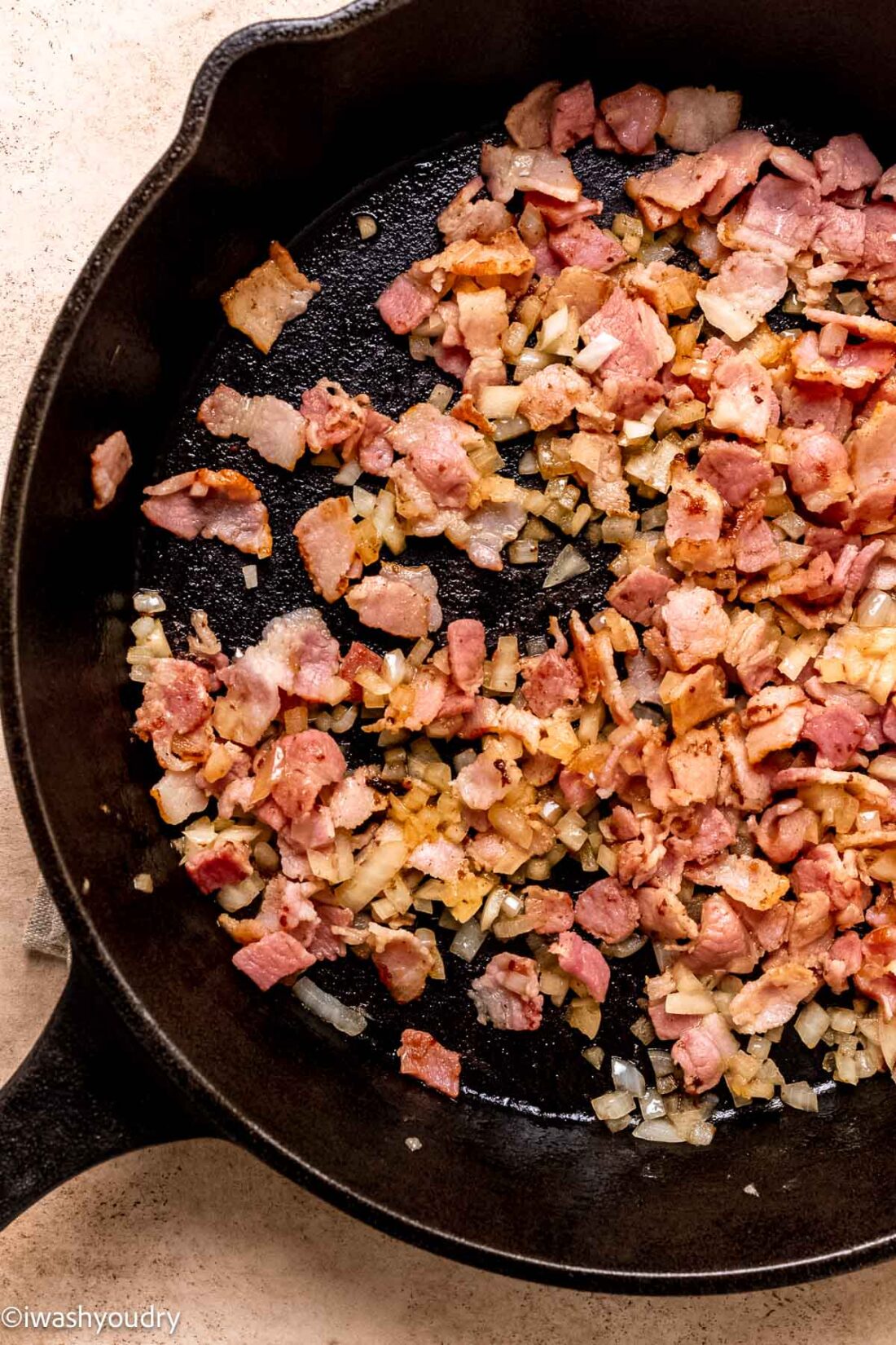 Cooked bacon and onions in cast iron frying pan. 