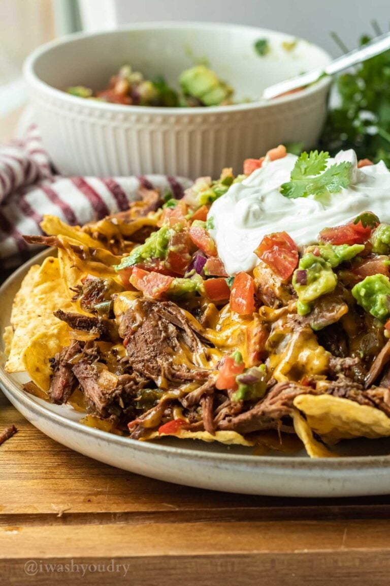 cooked plate full of carne asada nachos on wood cutting board.