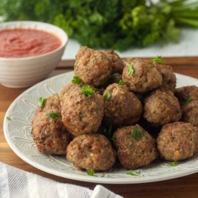 Pile of cooked air fryer meatballs on textured plate.