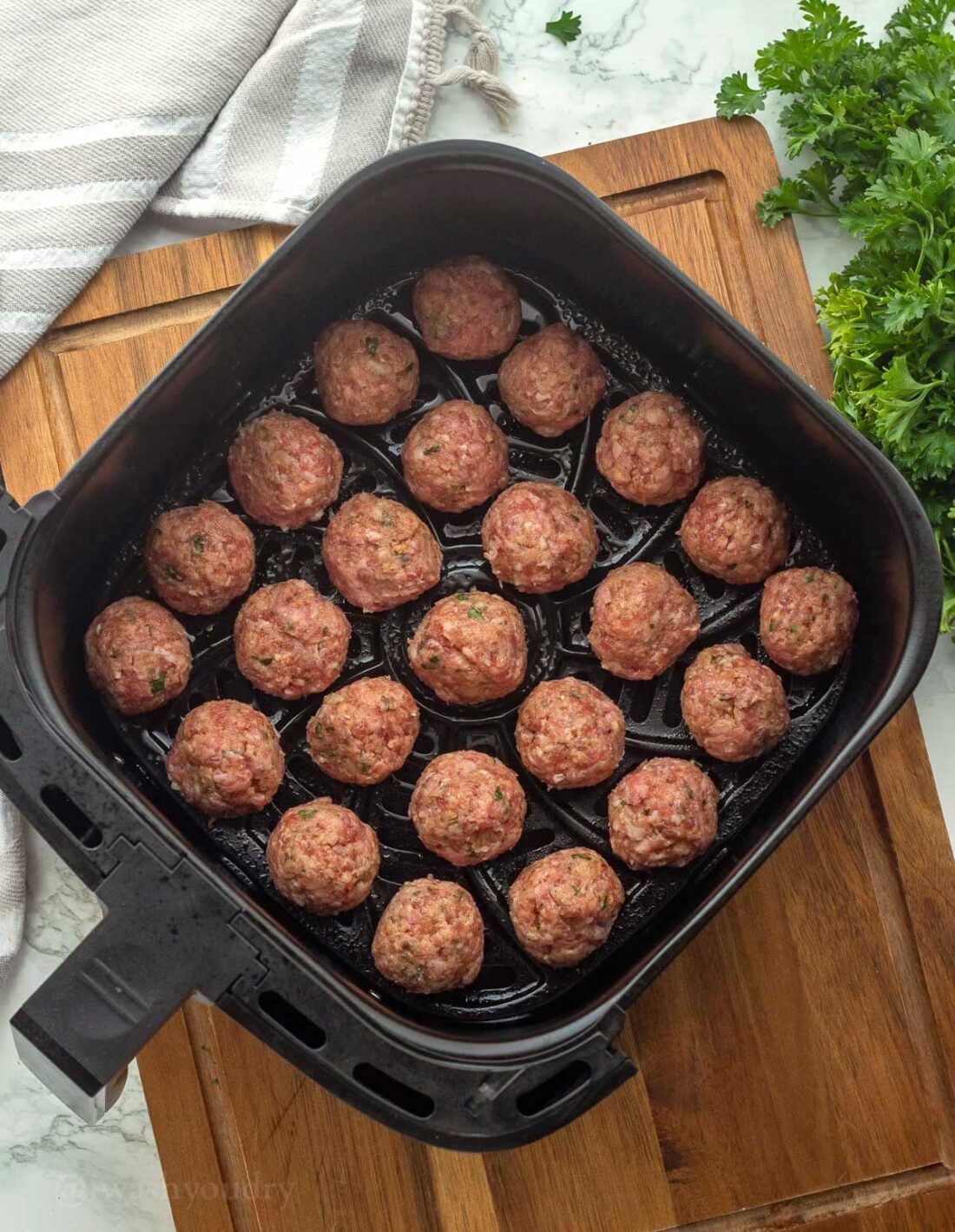 20 meatballs in an even layer in basket of air fryer. 