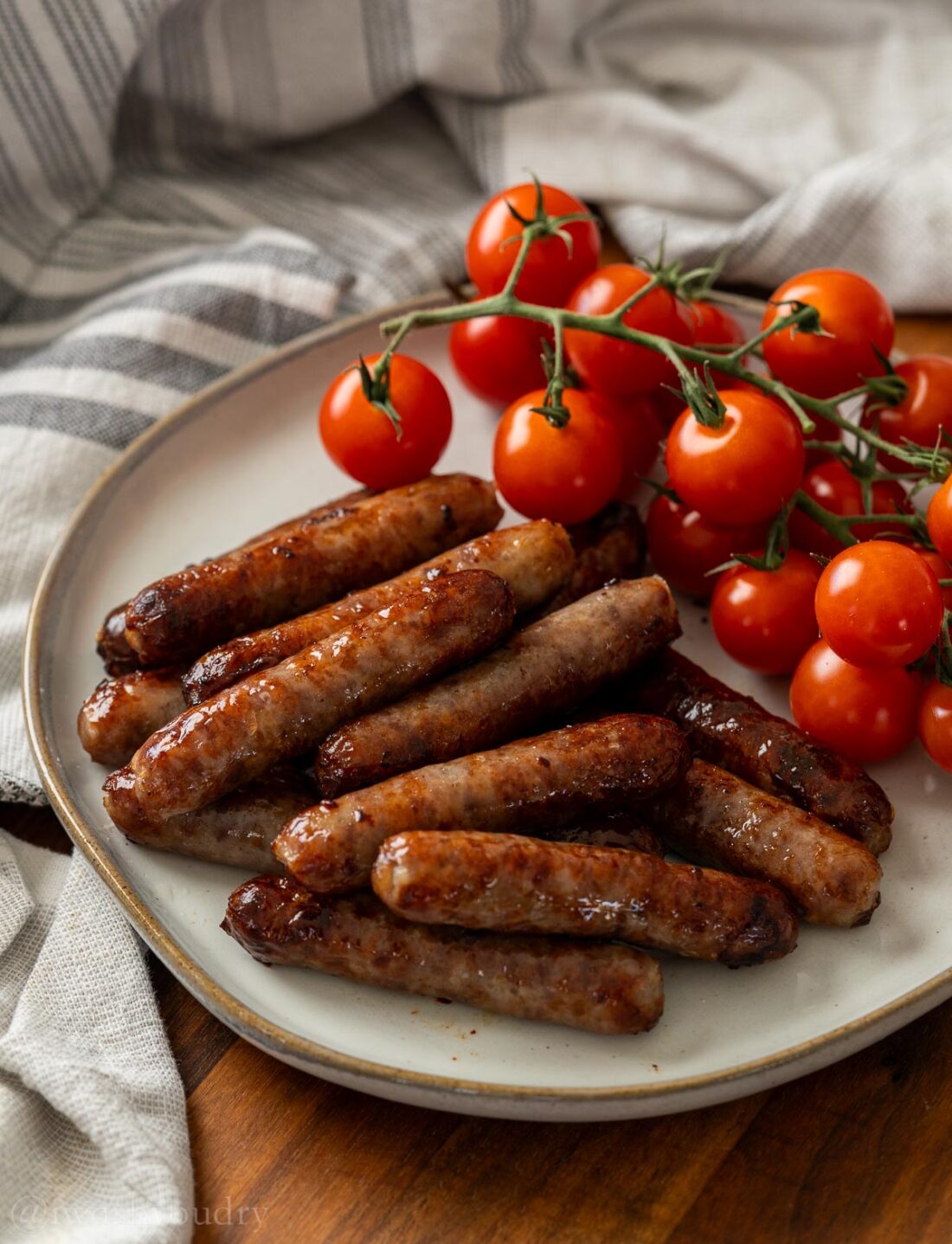 cooked air fryer sausage on a plate with tomatoes.