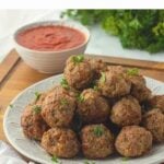 Pile of cooked meatballs on textured plate.