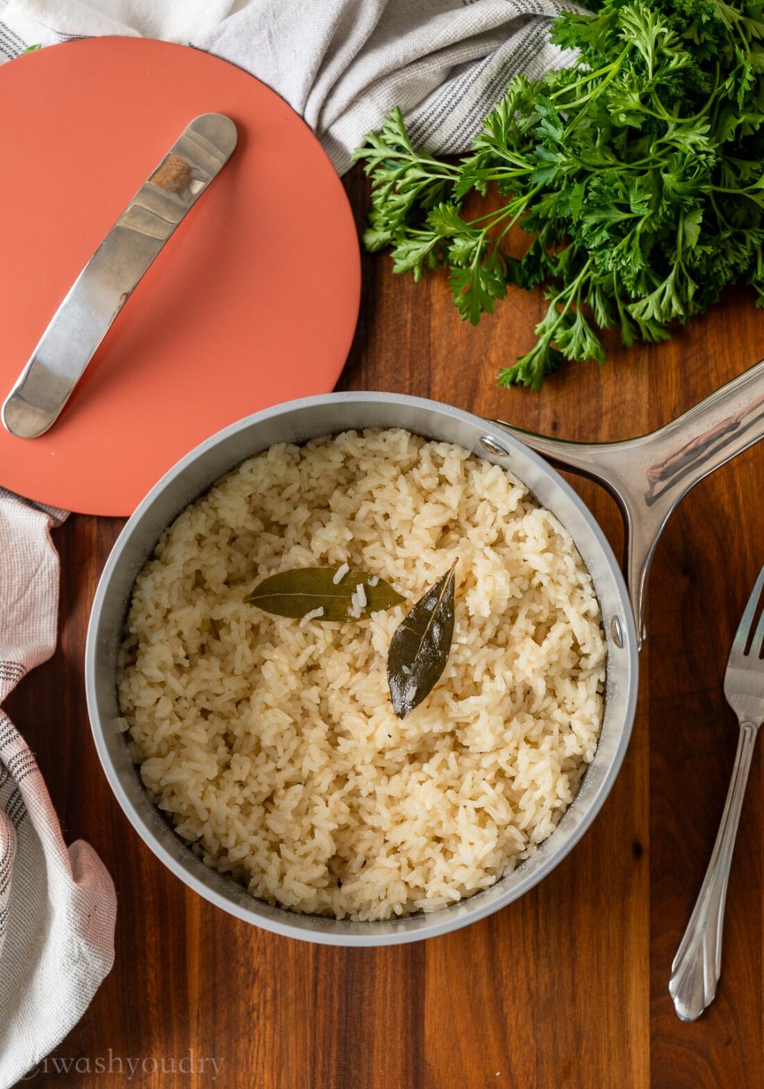 Cooked white rice with bay leaves in metal pot. 