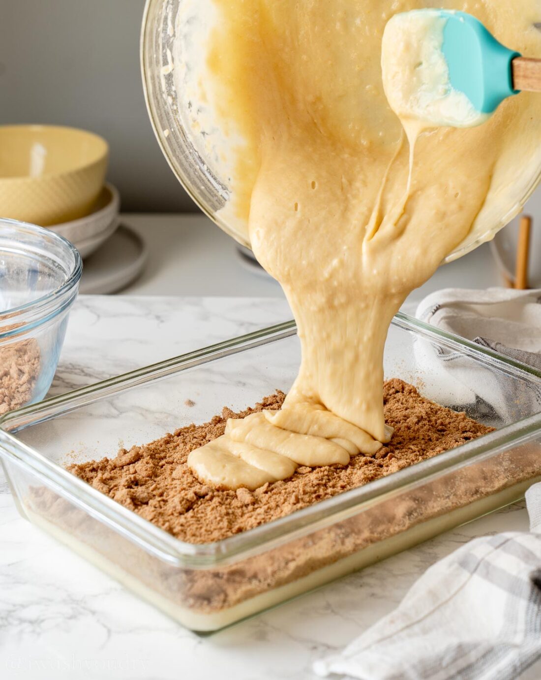 Pouring raw cake batter into baking dish with brown sugar topping. 