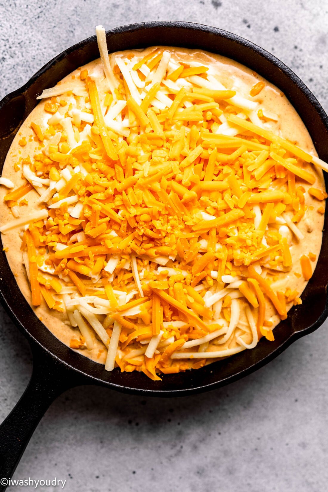 Shredded cheeses on top of buffalo chicken dip. 
