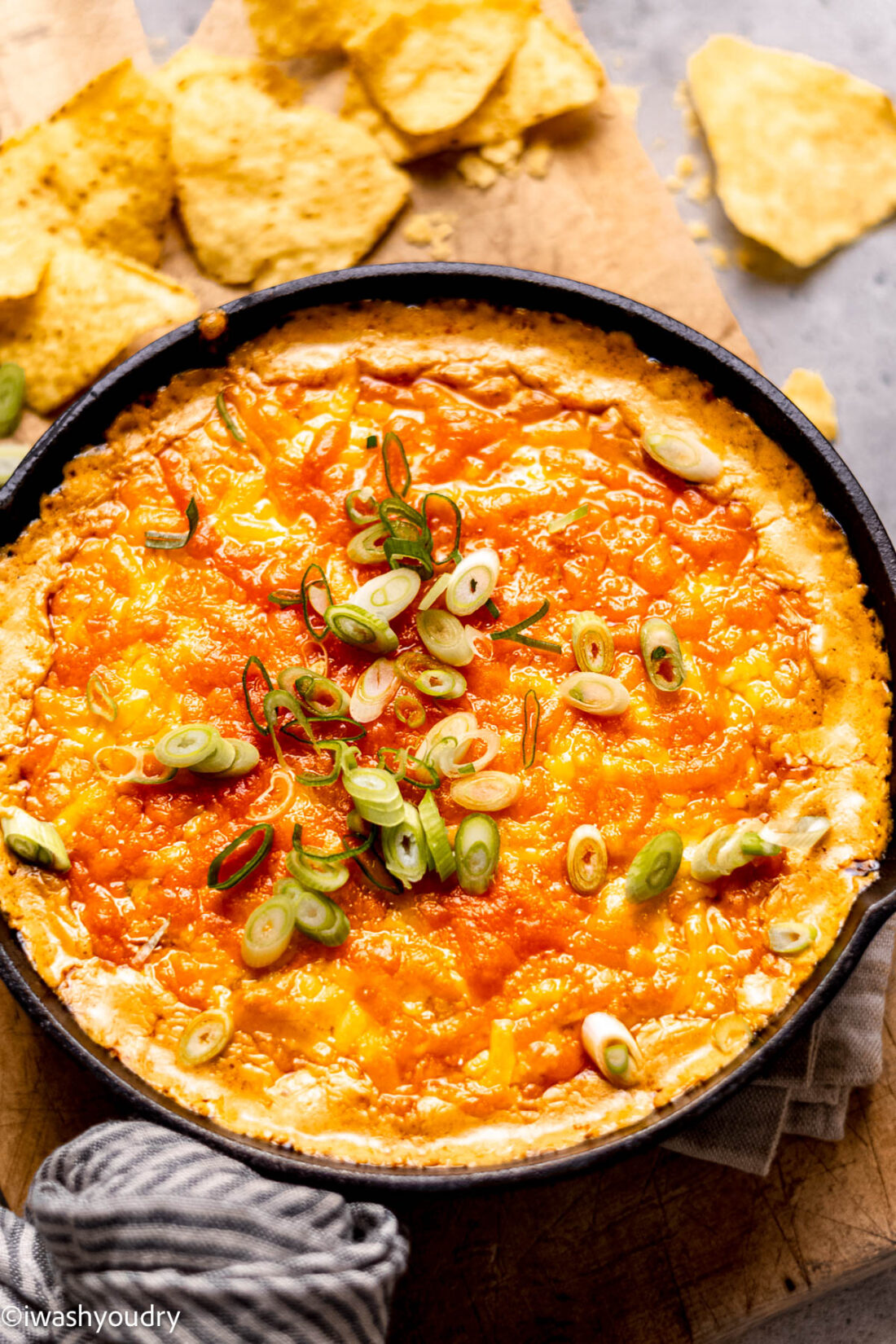 Pan of melted bufalo chicken dip with green onions on top. 