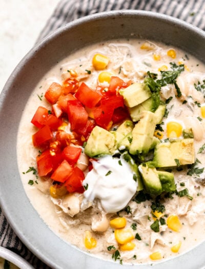 white chicken chili in bowl with tomatoes and avocado.