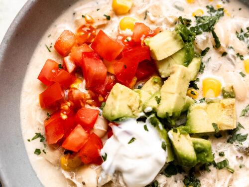 white chicken chili in bowl with tomatoes and avocado.