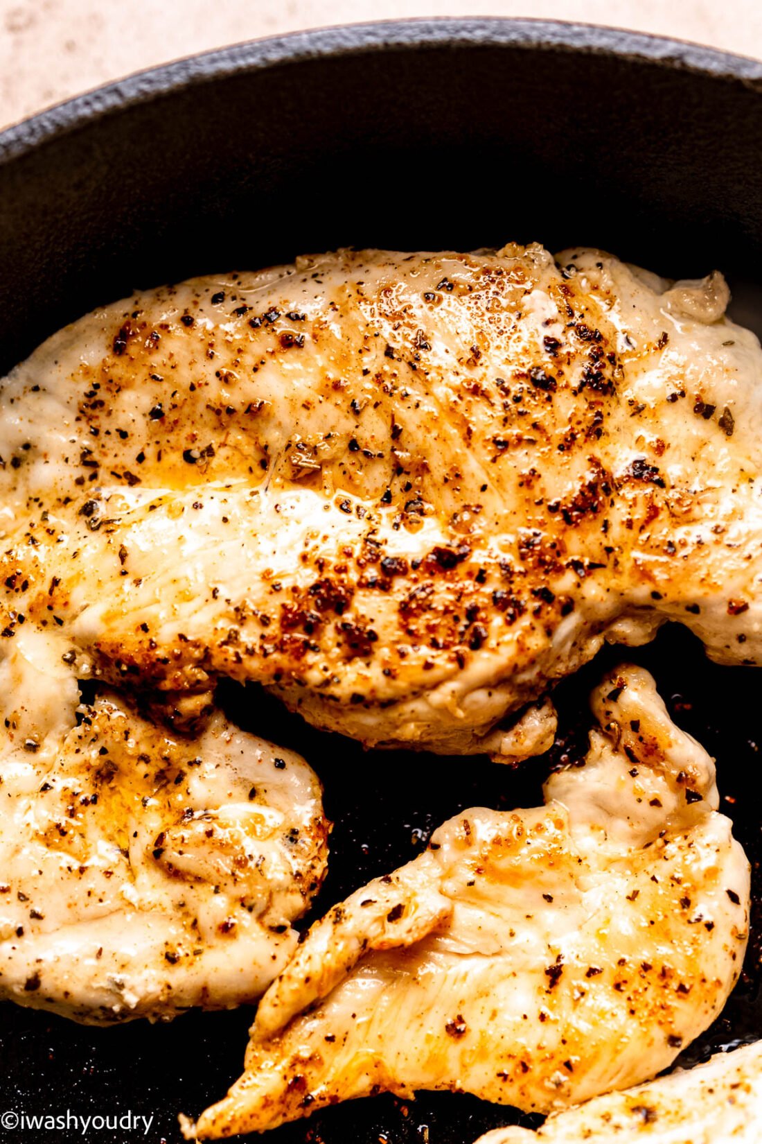 Browned chicken breast in metal frying pan. 