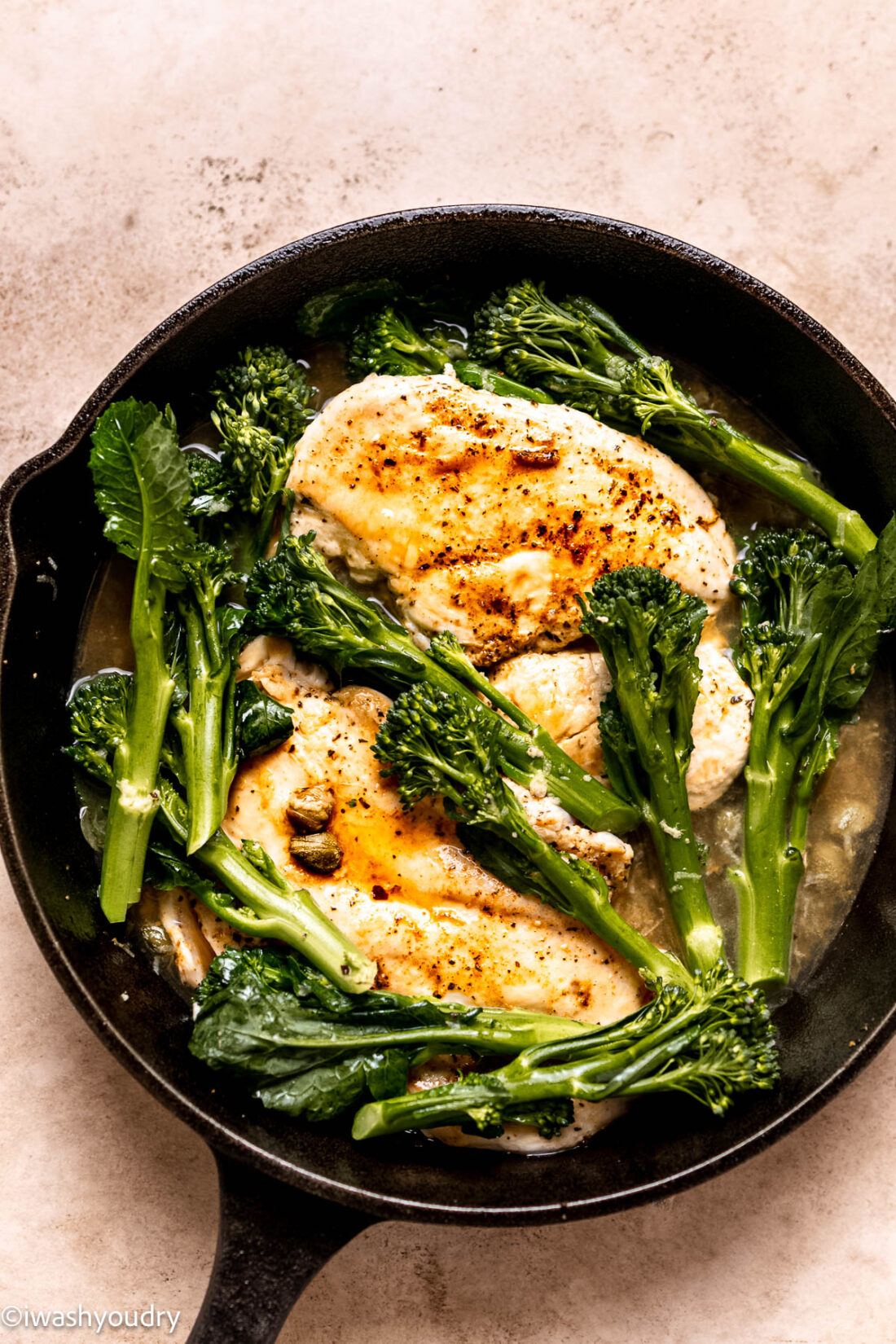 Cooking chicken and broccolini in frying pan. 