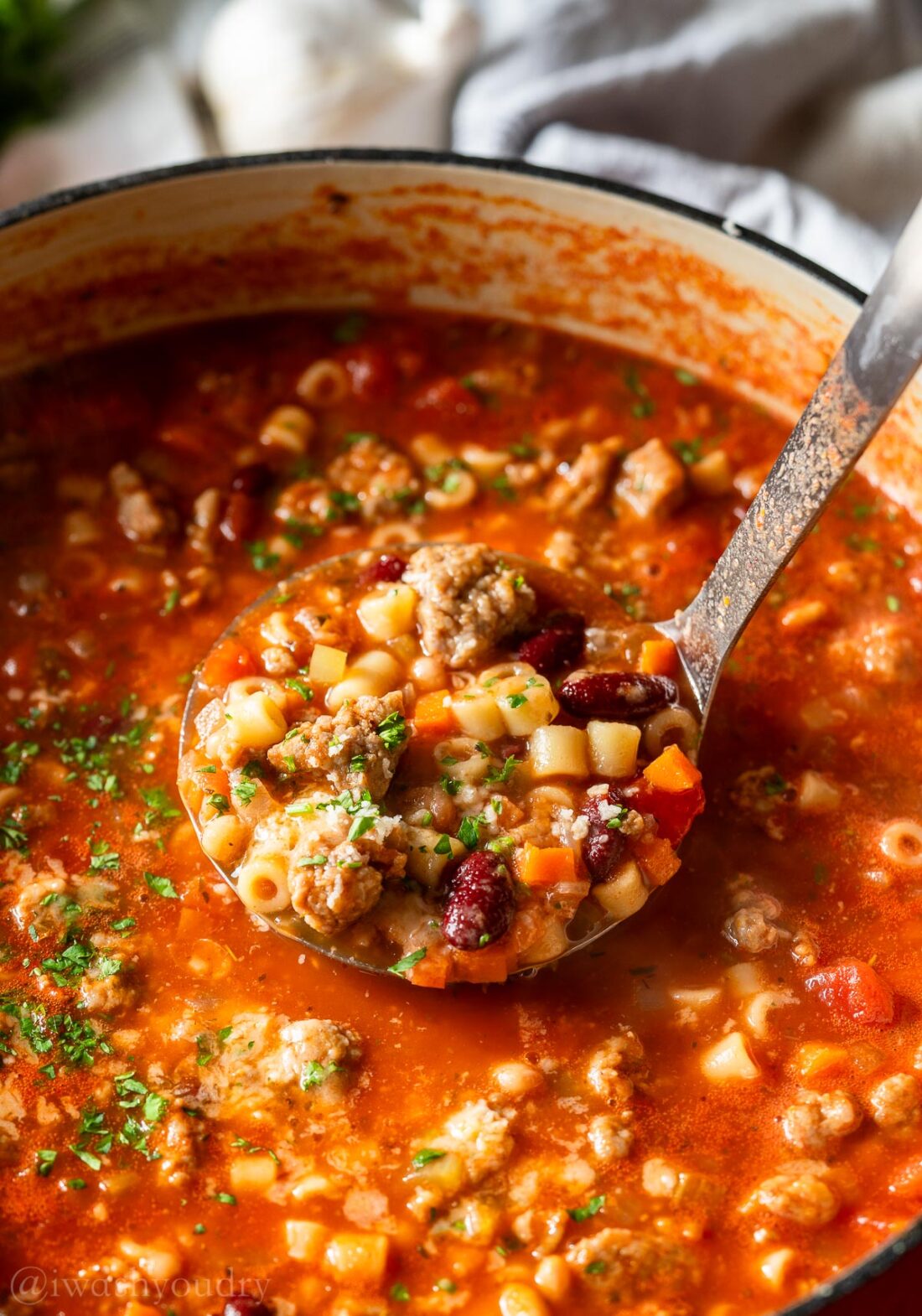 pot of pasta e fagioli with spoon picking up a hearty serving.
