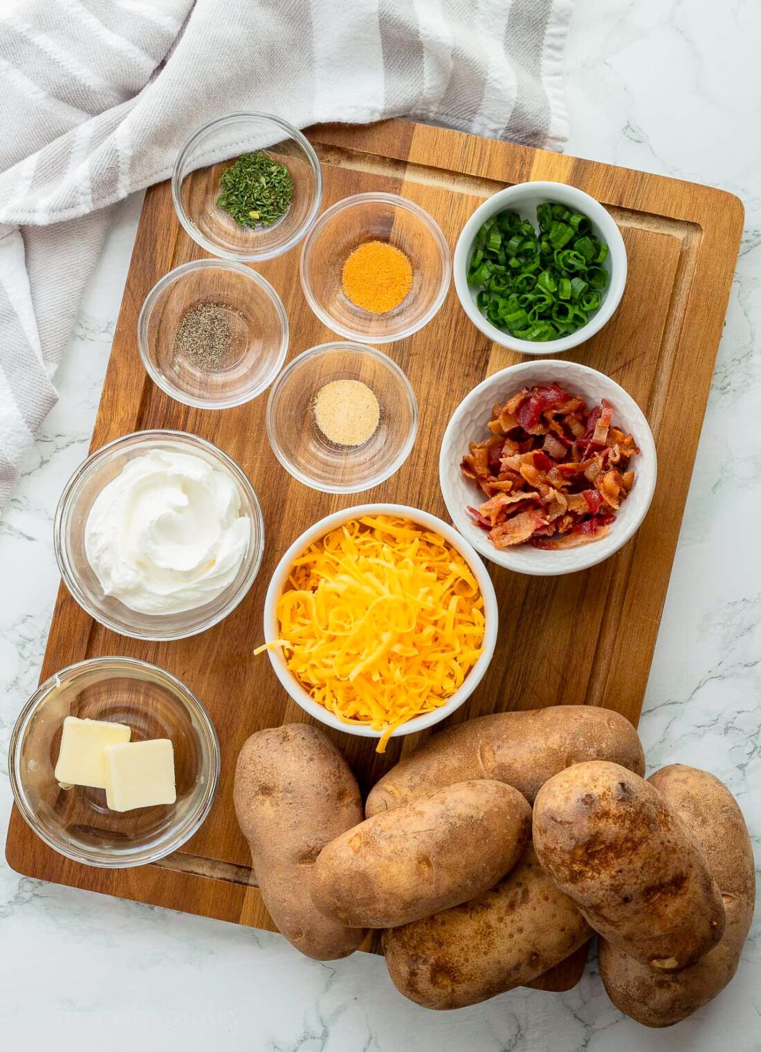 Ingredients for crispy baked potato skins on wooden cutting board.