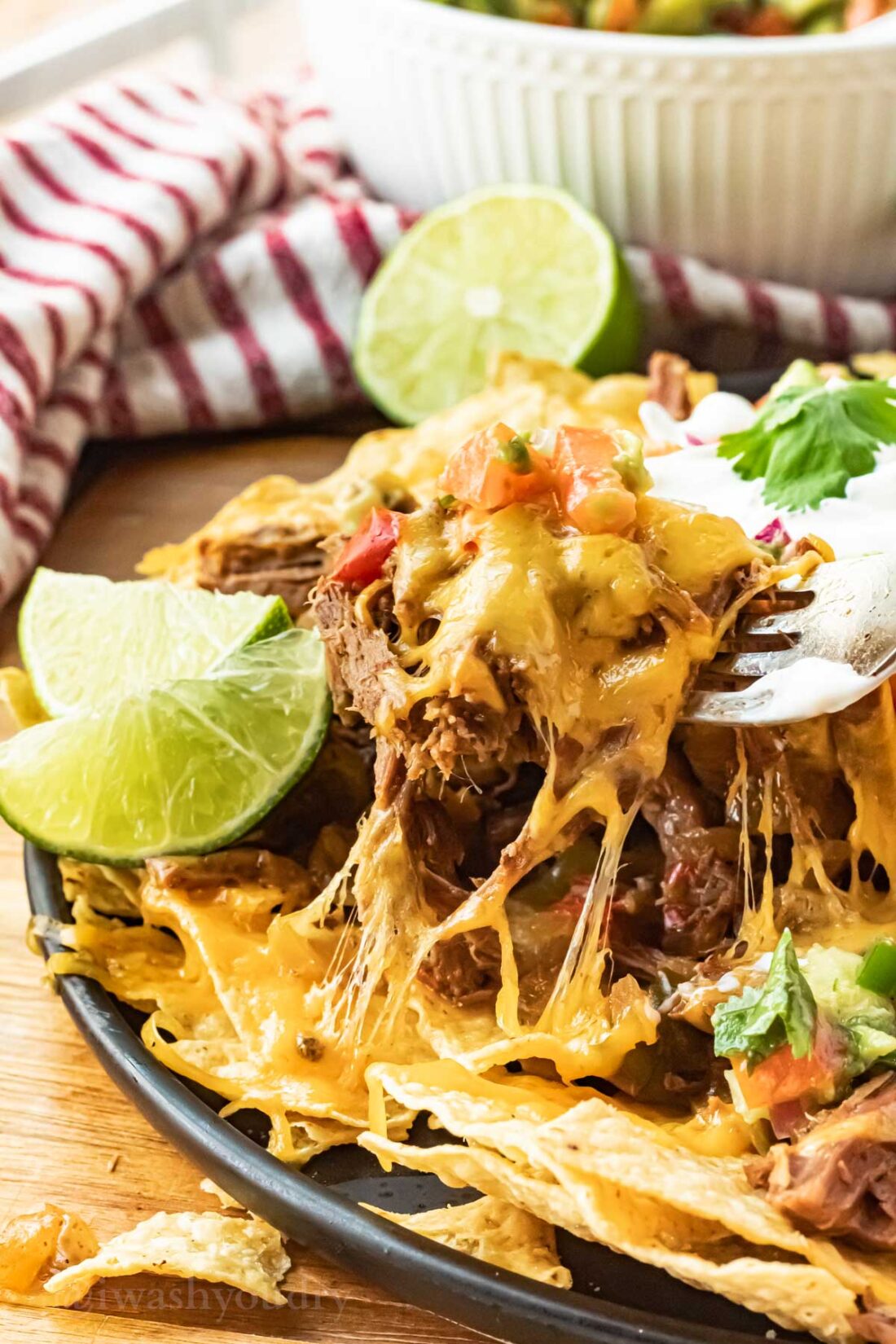 bite of shredded beef nachos on fork with cheese.